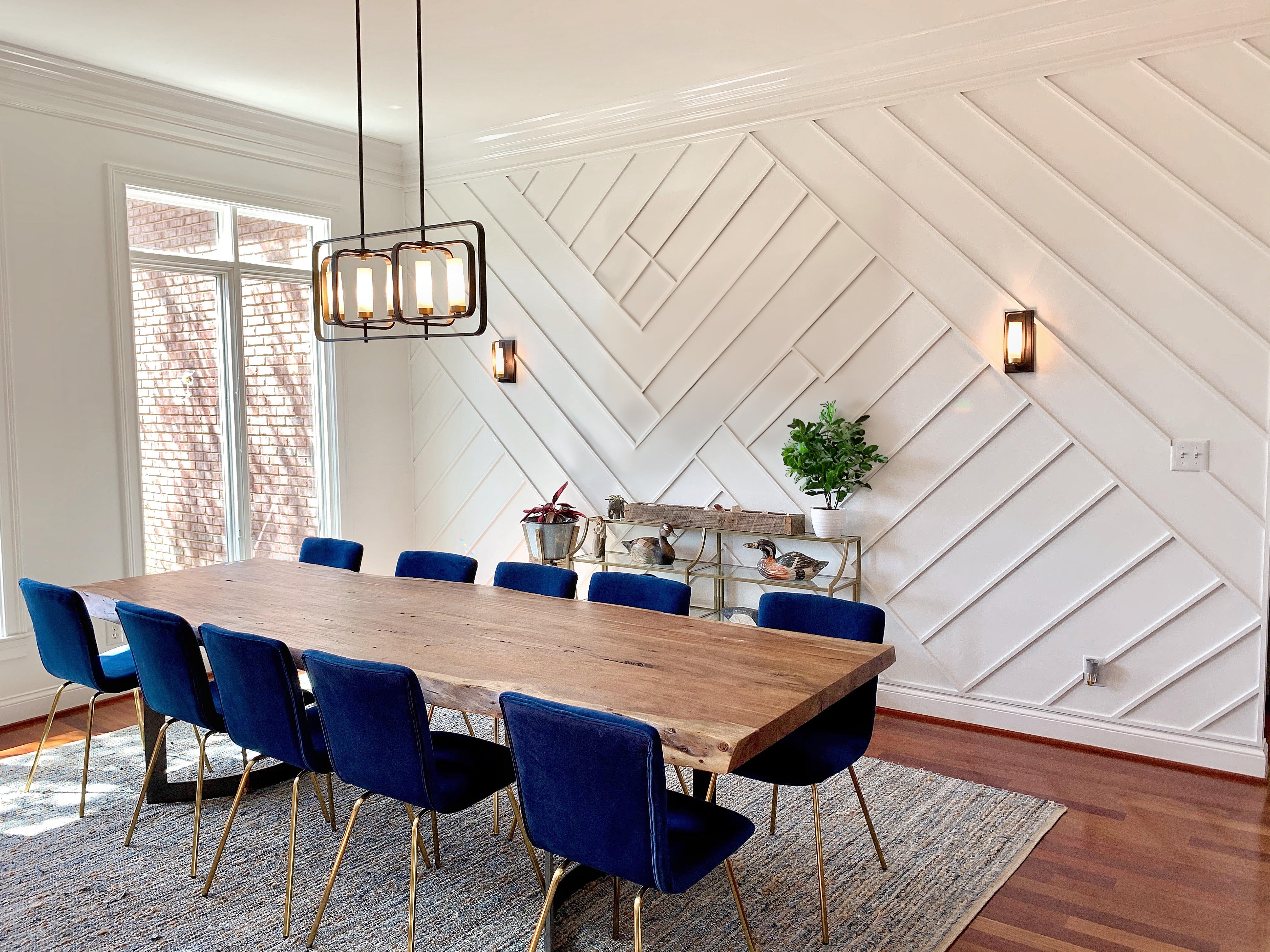 Table en bois, chaises bleues, murs blancs, éclairage suspendu
