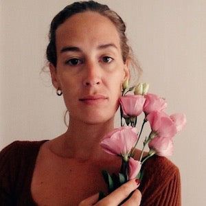 Femme tenant des fleurs roses, regard sérieux, chemise marron