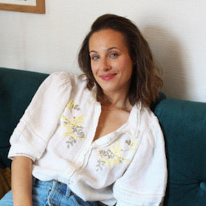 Femme sur bleu, sourire, chemise blanche, mur blanc